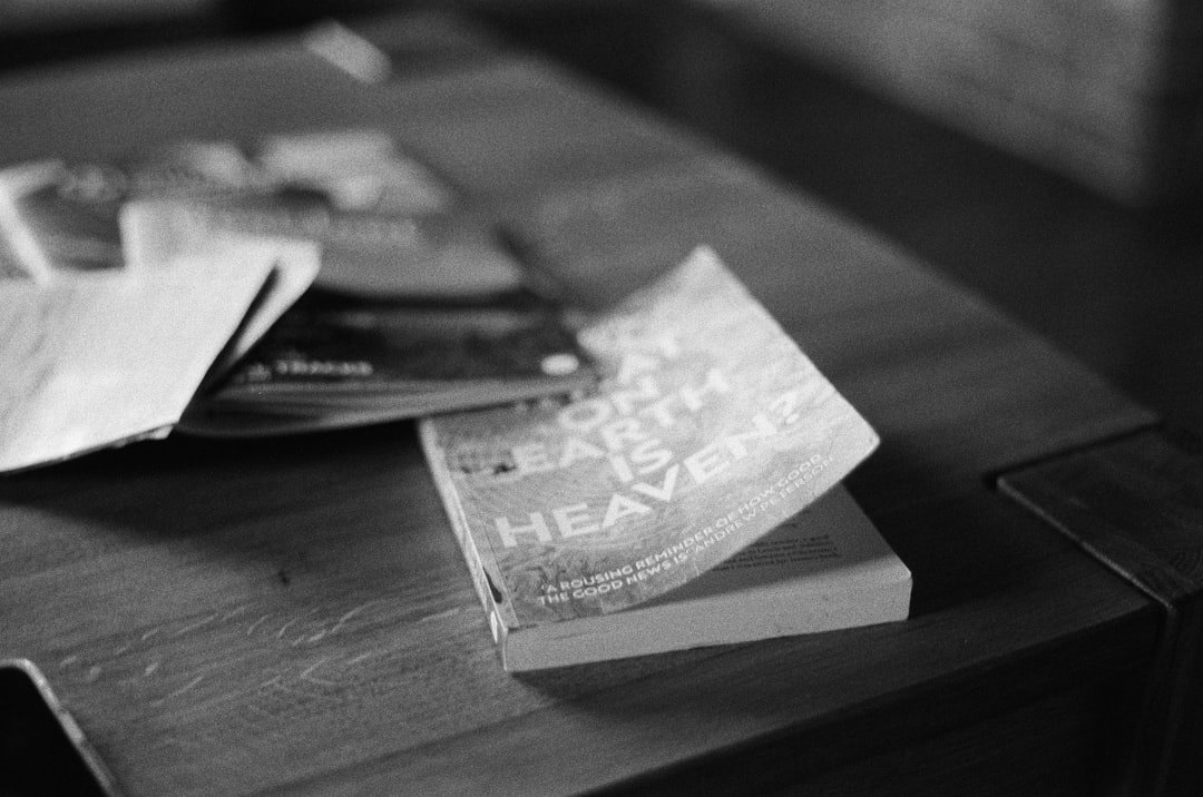 Stack of books on a wooden table with reading glasses