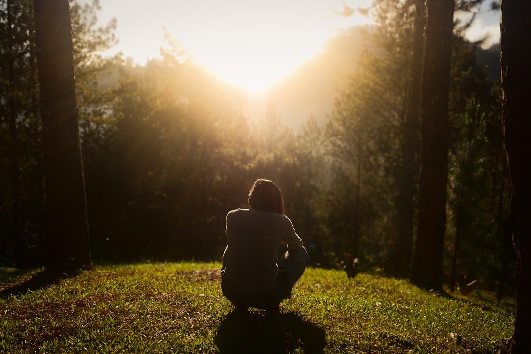 Person meditating peacefully outdoors at sunrise